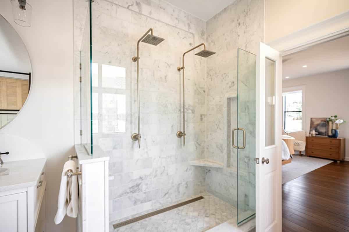 Shower with full stall doors, round mirror and wood floors