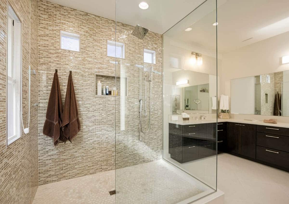 Shower with glass walls with no door and brown towels on wall
