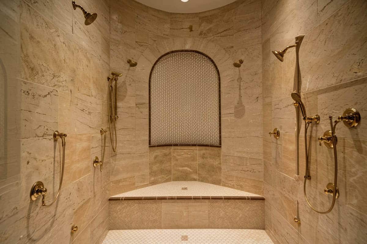 Travertine clad shower with gold fixtures