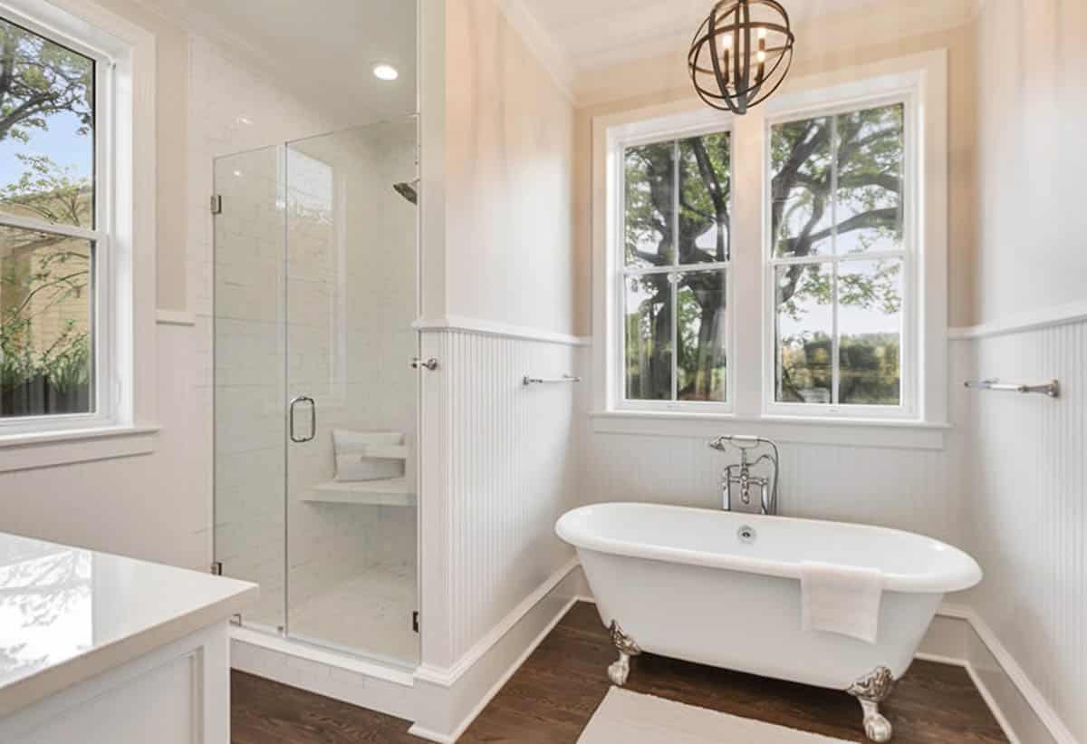 Bathroom with small corner shower, beadboard wainscoting and globe lights