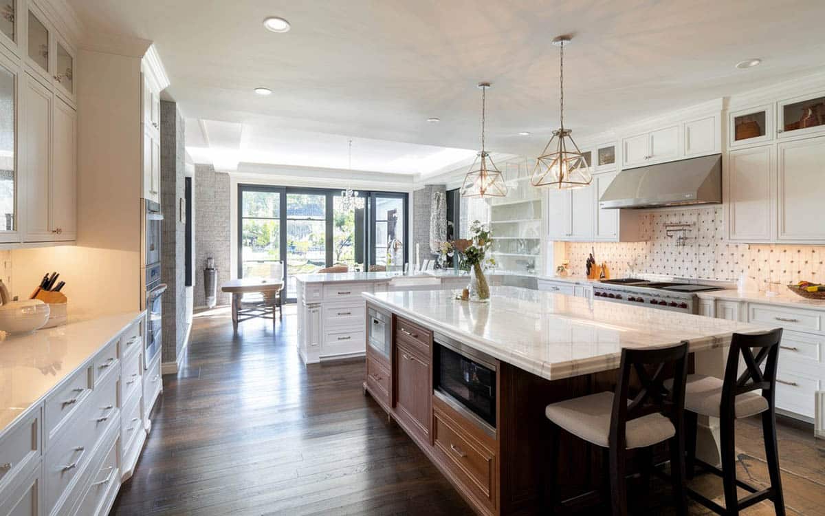 Kitchen with white cabinets and island with seating for two and long peninsula