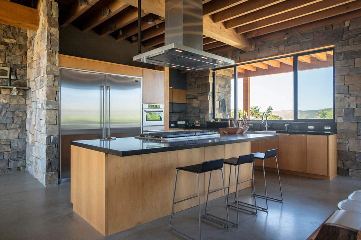 Chefs wood kitchen with slate accent wall, large oven hood and black counters