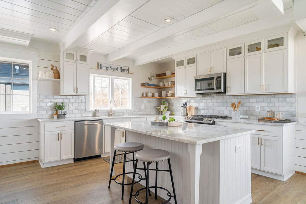 Kitchen with shiplap ceiling, white cabinets, marble countertops and wood flooring