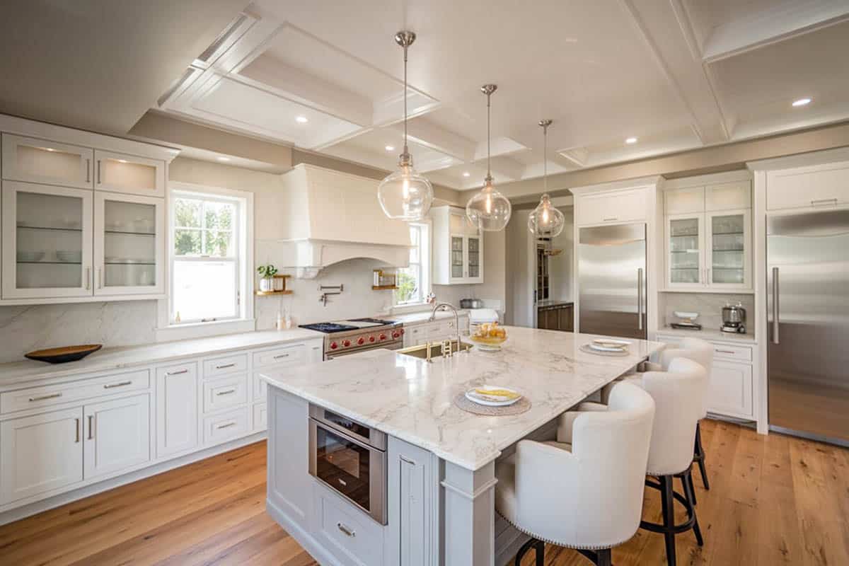 White kitchen with calacatta carrara marble counter and moody blue color island with bar stool seating