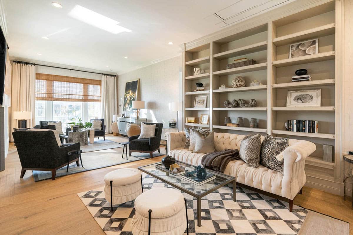 Bookshelves in taupe finish, floor to ceiling curtains and lounge chair