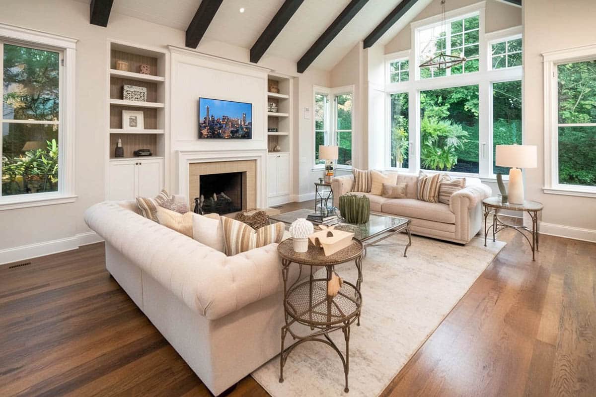 Off-white walls matching the couches, accent pillows with view of trees