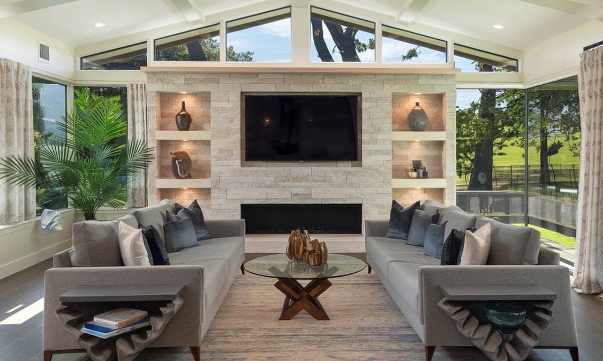 Room with stacked stone accent wall, grey couches and wraparound windows