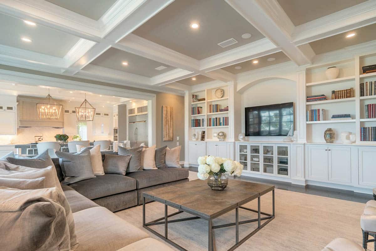 Room with boxed ceiling, taupa fabric sofa and white staircase with wood railings