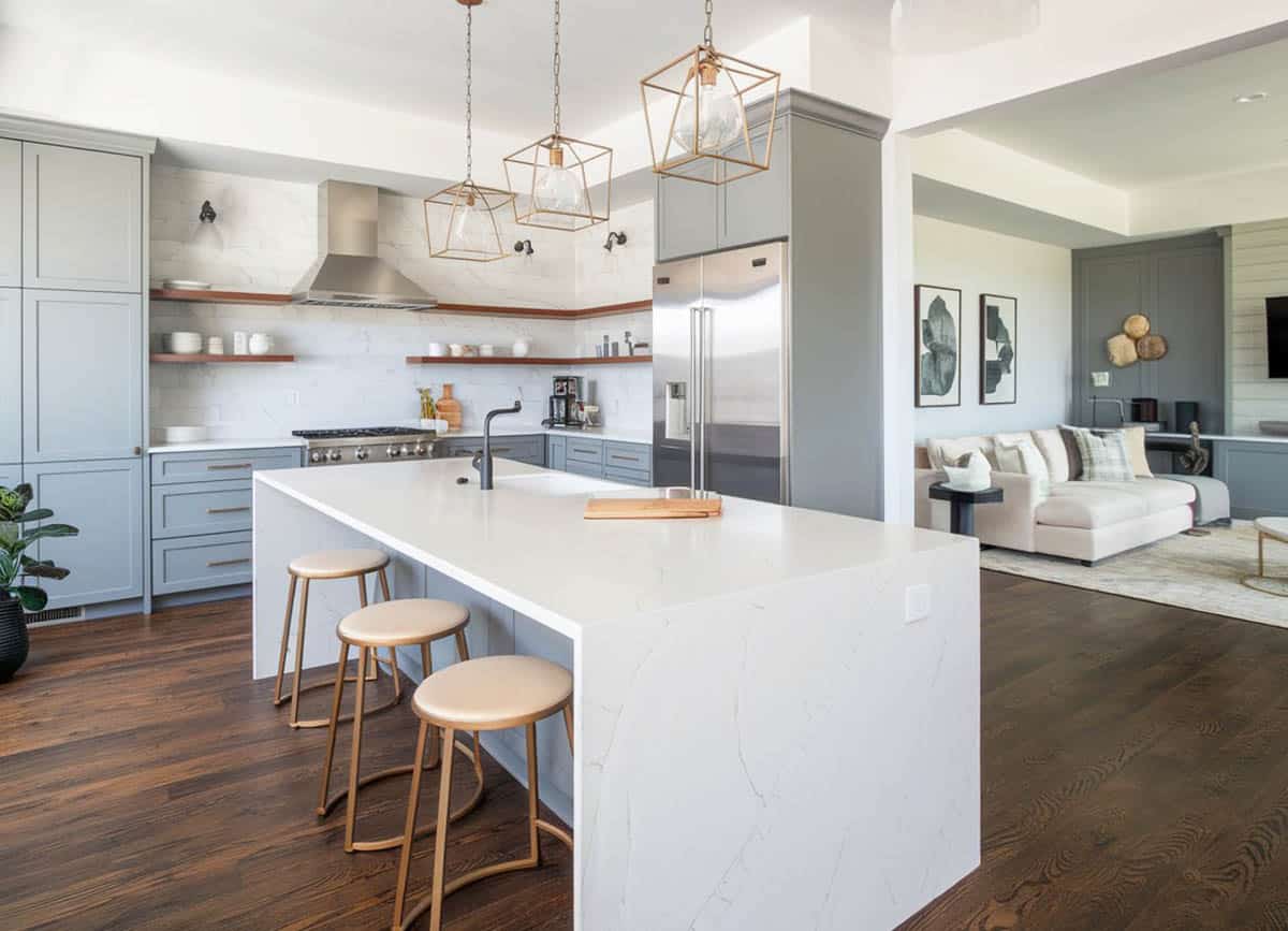 Gold finishes and gray shaker cabinets with white waterfall quartz island