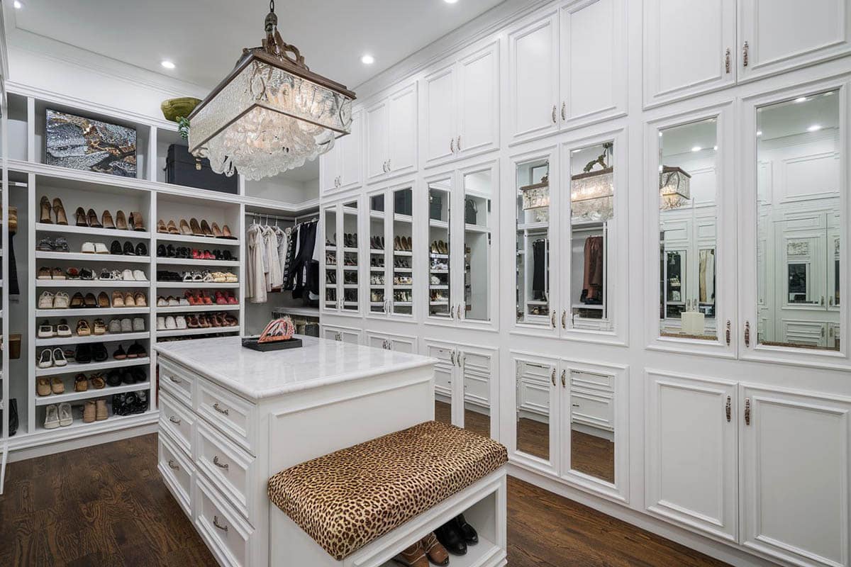 Beautiful walk-in closet with shoe storage, marble island and hardwood flooring