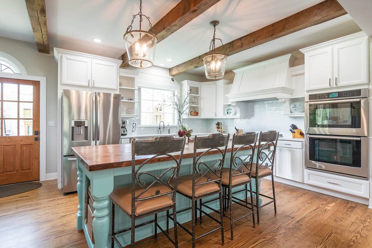 Kitchen with white cabinets light green island wood beam ceiling wood flooring