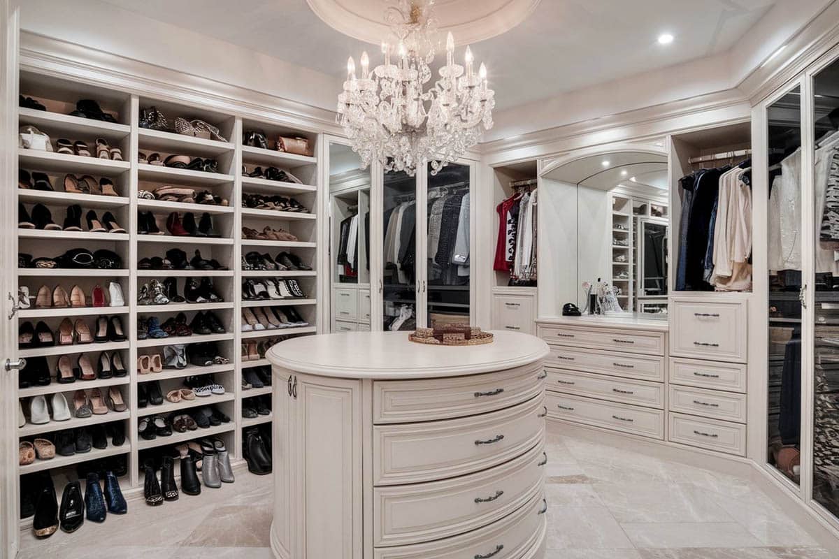 Luxury closet with shoe shelving racks, oval island, chandelier and vanity makeup station