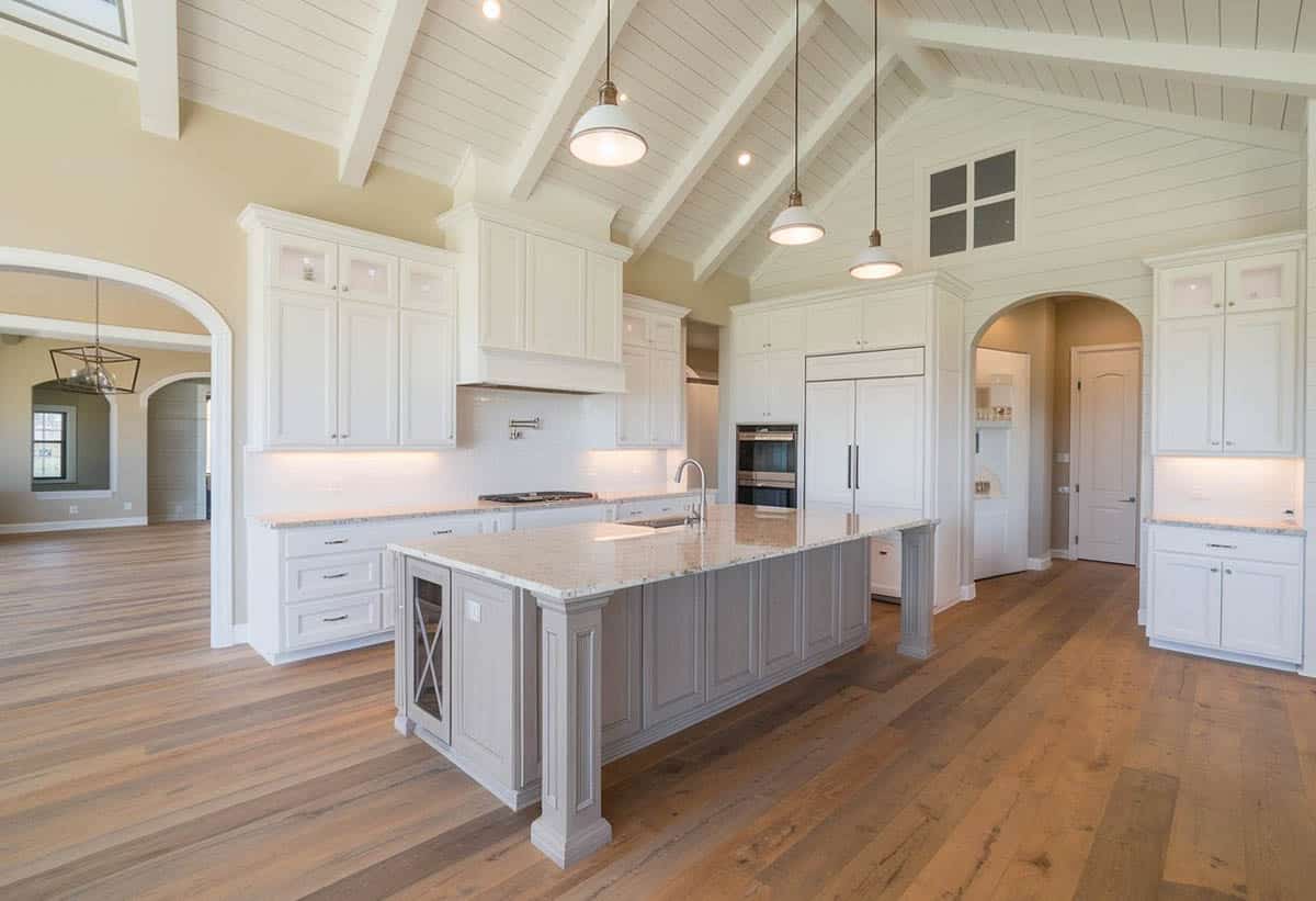 White kitchen with arched shiplap design ceiling and gray beadboard island