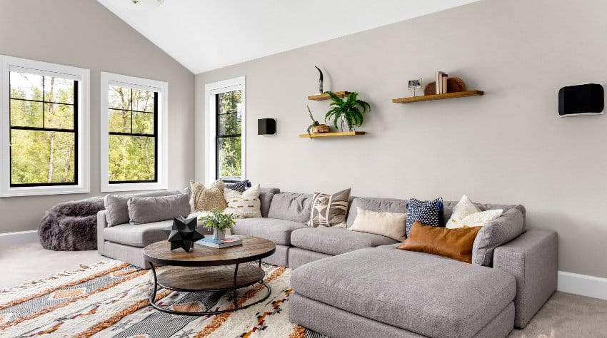 Room with geometric design carpet, grey sectional and cantilever shelves