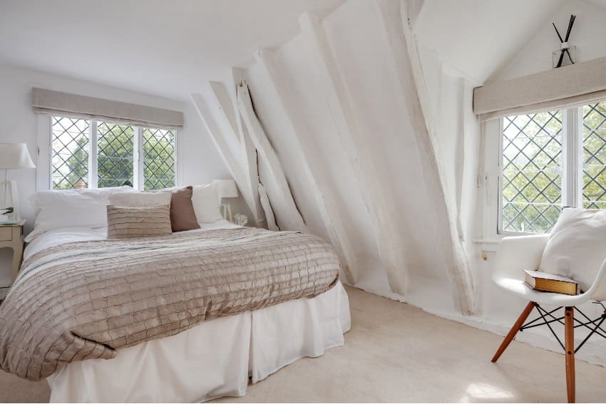 Bedroom with white chair, brown pillows and quilt