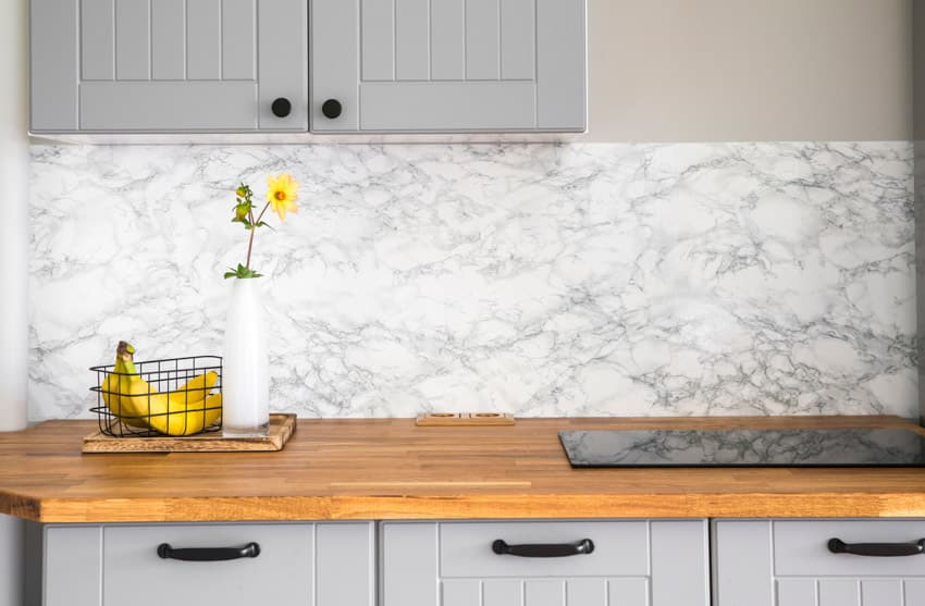 Farmhouse kitchen with cedar countertop, marble backsplash, stove, and gray cabinets