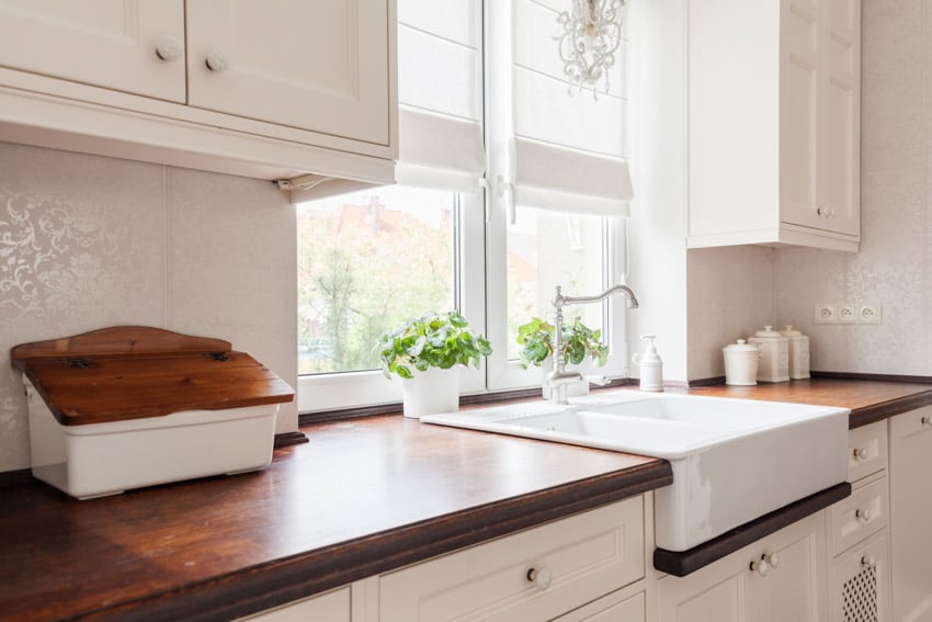 Farmhouse kitchen with cedar slab countertop, sink, faucet, cabinets, and window