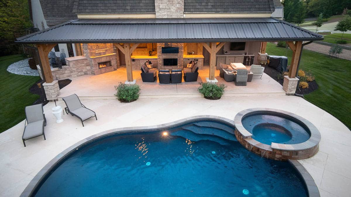 Backyard cabana with kitchen, fireplace, tv next to pool and spa