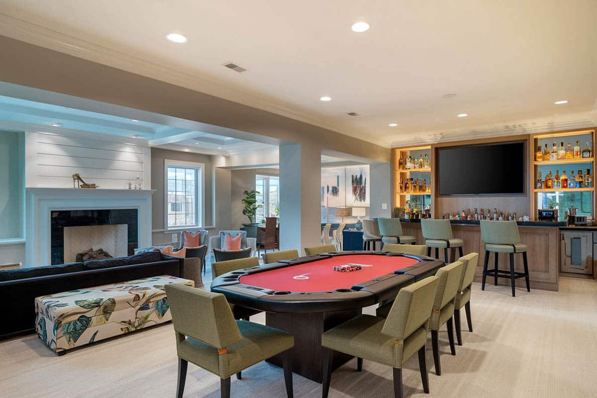 Card table with green fabric seats and backlit bar and shiplap fireplace