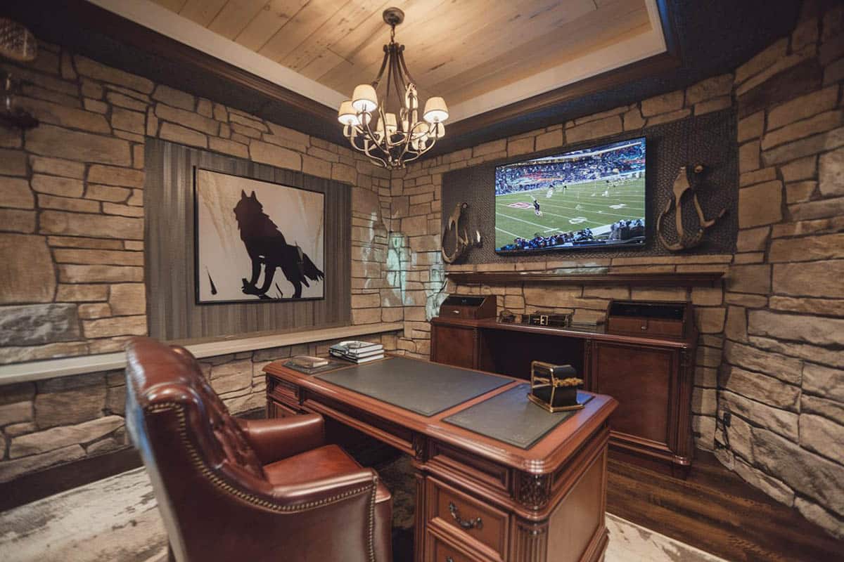 Stone wall office with desk, wood flooring and big screen television